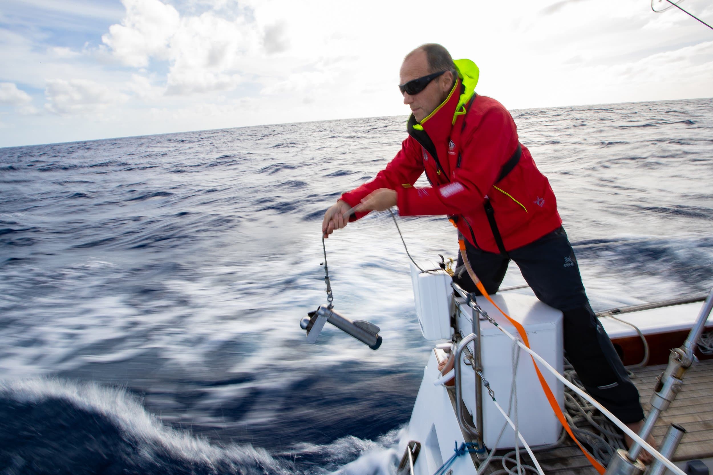 A seafarer using an ocean sampling device from a yacht